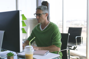 Front view of Caucasian businessman working on computer at desk in modern office